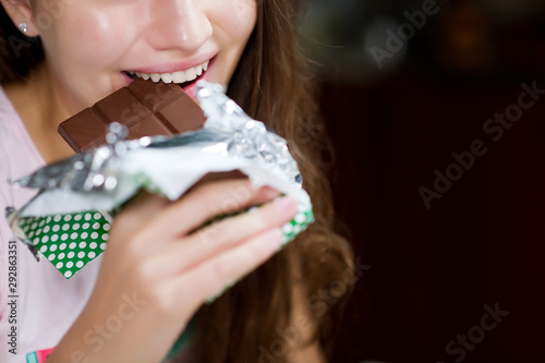 woman bites a chocolate bar. Close-up