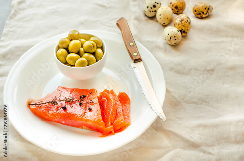 Slices of Salted Raw fish fillet with olive  quail eggs on white plate. Products good for healthy hair. Selective focus