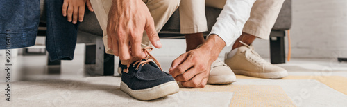 panoramic shot of father tying shoelaces to son