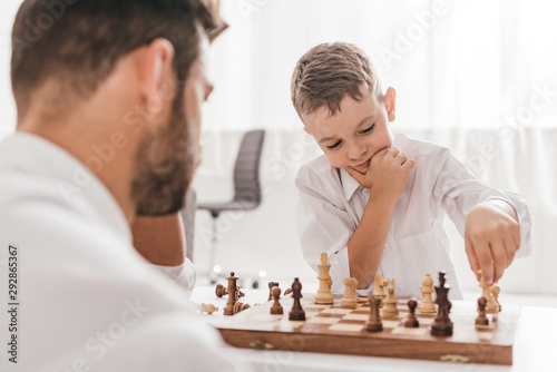 selective focus of dad and son playing chess together at home
