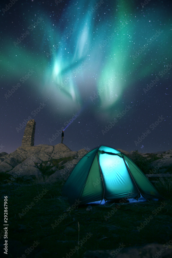 Camping in tent under the aurora dancing lights in the night sky