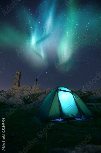 Camping in tent under the aurora dancing lights in the night sky