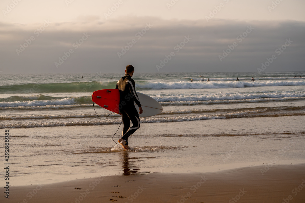 Strong surfer man with surfboard surfing at sunset or sunrise. Strong surfer man with surfboard surfing at sunset or sunrise.