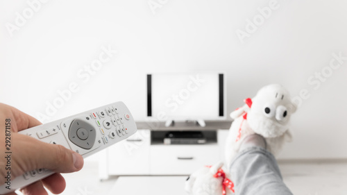 Woman looking at TV with legs on the table in living room.