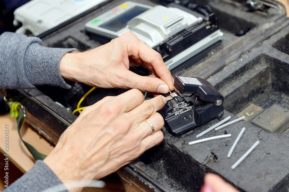 An optical fiber welder works with a fiber cleaver. A technician cuts and fusion fiber optic cables. An optical fiber welder works with a fiber cleaver. A technician cuts and fusion fiber optic cables.