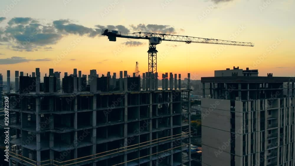 Building machinery and high-rise houses in progress at sunset Building machinery and high-rise houses in progress at sunset
