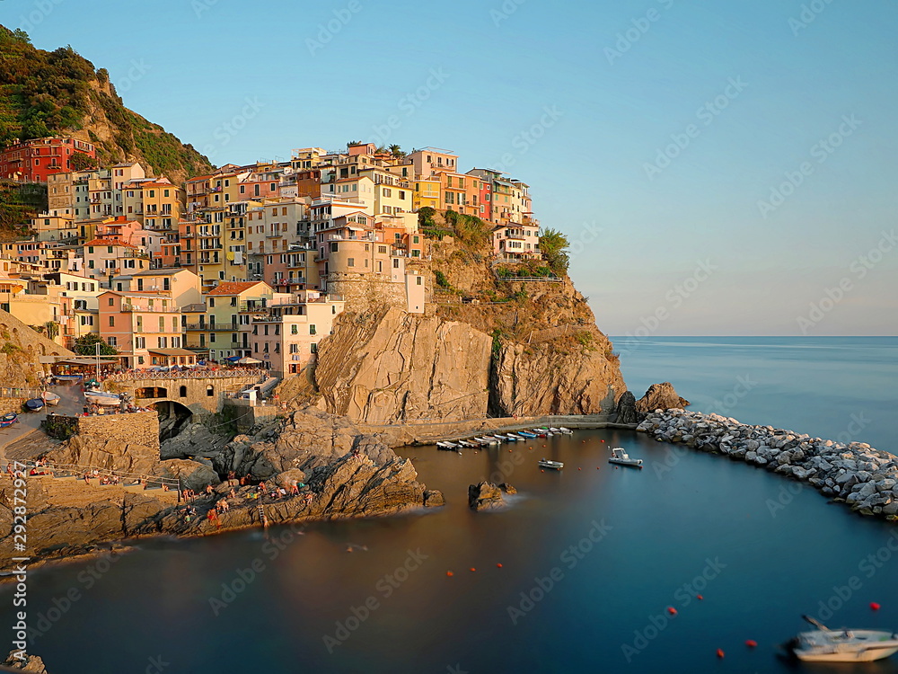 beautiful view of Manarola at sunset, characteristic village of the Cinque Terre (Italy) with colorful houses and on a cliff, with water between the rocks in the lower part forming a blue heart