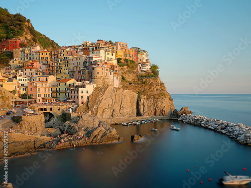 Fototapeta Naklejka Na Ścianę i Meble -  beautiful view of Manarola at sunset, characteristic village of the Cinque Terre (Italy) with colorful houses and on a cliff, with water between the rocks in the lower part forming a blue heart