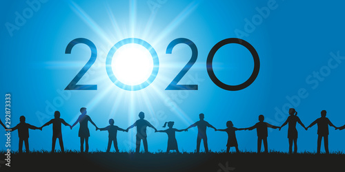 Un groupe d’hommes et de femmes de tous les âges ainsi que des enfants qui se donnent la main face au soleil et à l’année 2020 qui s’inscrit dans le ciel.