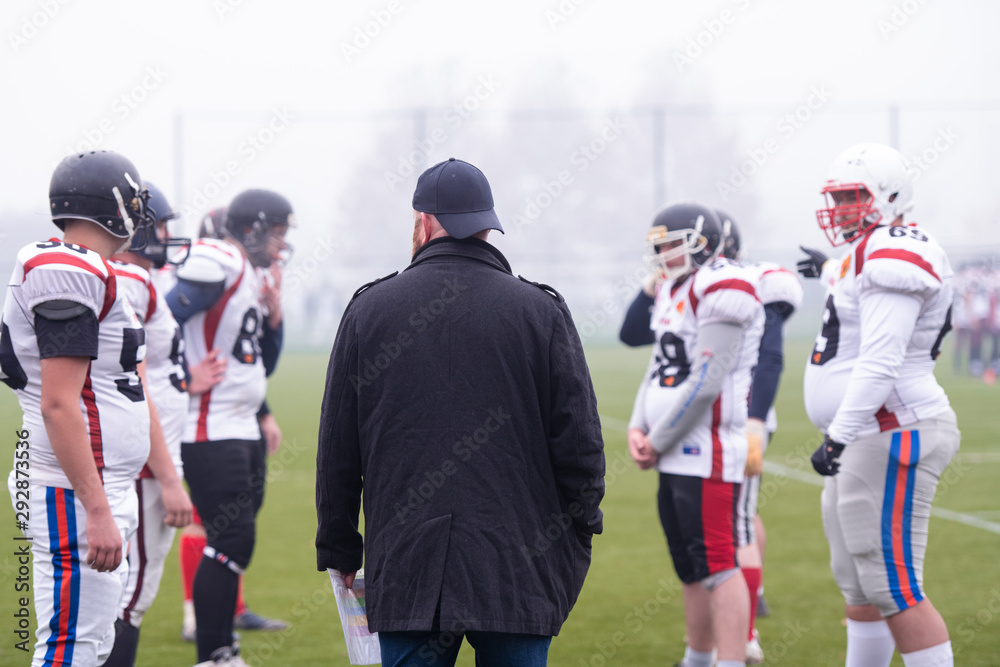 Fototapeta premium american football players discussing strategy with coach