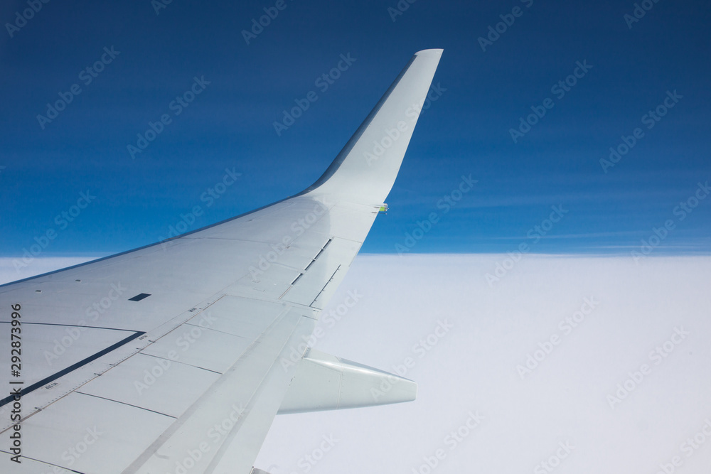 Fototapeta premium View through the window of an airplane wing against the blue sky.