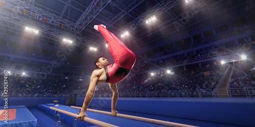 Foto Male athlete doing a complicated exciting trick on parallel bars in a professional gym