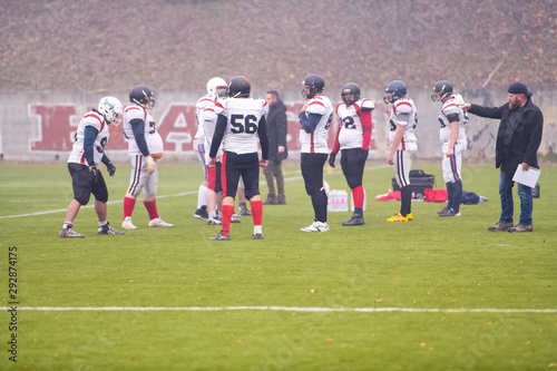 american football players discussing strategy with coach