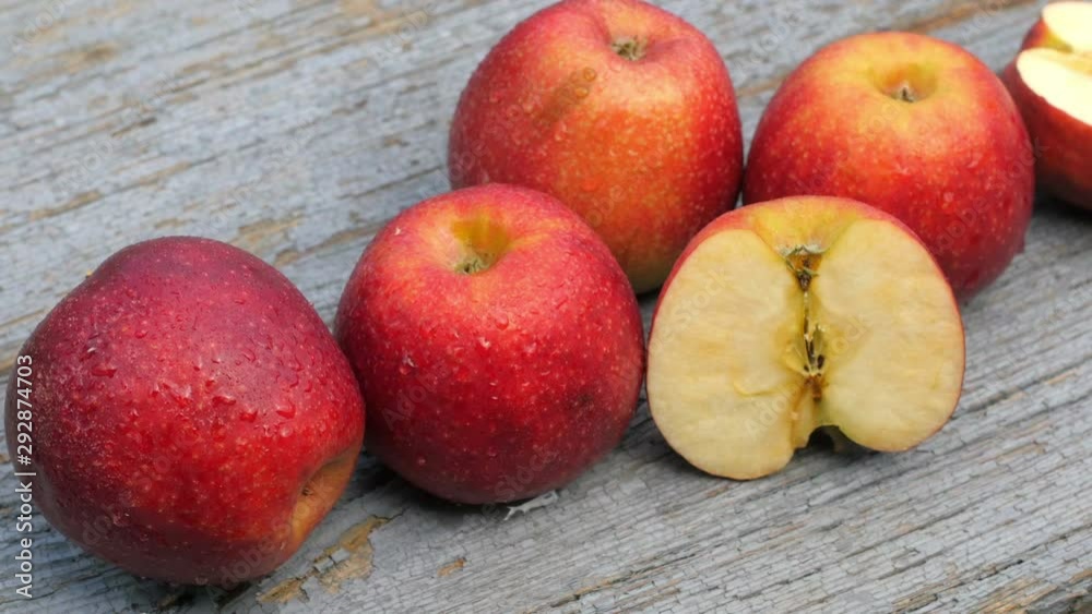 Fresh red apples covered with droplets of water lie on a wooden table. Fresh fruits. Half an apple. Healthy food concept. Fresh red apples covered with droplets of water lie on a wooden table. Fresh fruits. Half an apple. Healthy food concept.