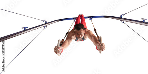 Male athlete doing a complicated exciting trick on gymnastics rings on white background. Isolated Man perform stunt in bright sports clothes