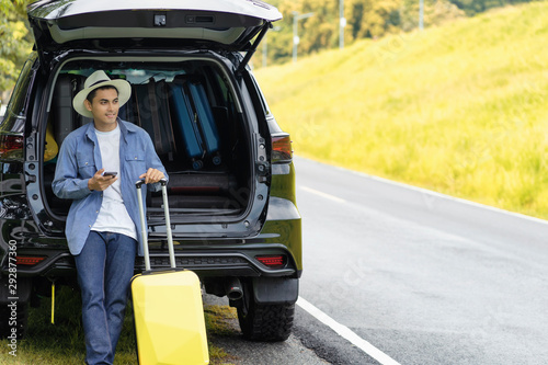 The men hold the phone and the suitcase.Car stand hatchback prepare for travel by car.A man stood in the car with his mobile phone and luggage, ready to travel.Vintage tone