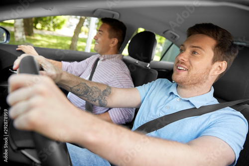 car driving lesson and carpooling concept - instructor on passenger seat and young driver laughing