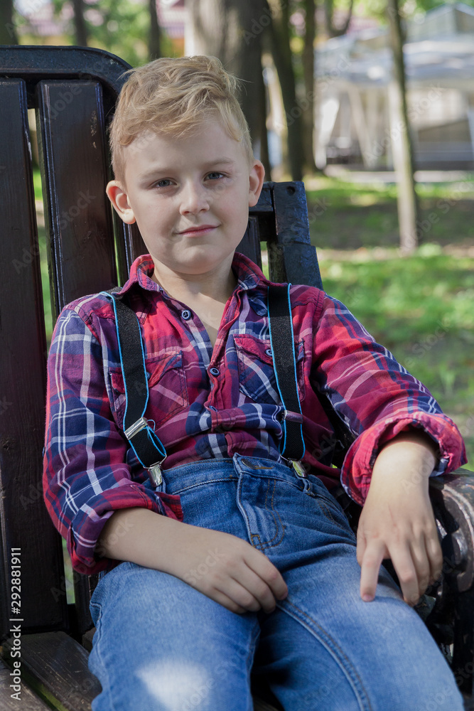 Beautiful boy 7 years old sits on a bench in the park. Beautiful boy 7 years old sits on a bench in the park.