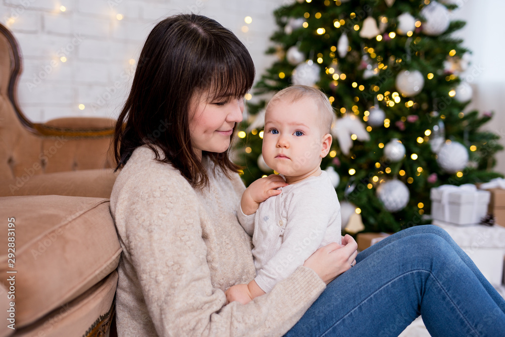christmas, happiness and family concept - happy mother and little baby girl near decorated christmas tree christmas, happiness and family concept - happy mother and little baby girl near decorated christmas tree