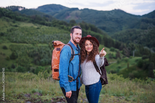 Young tourist couple travellers with backpacks hiking in nature, talking.