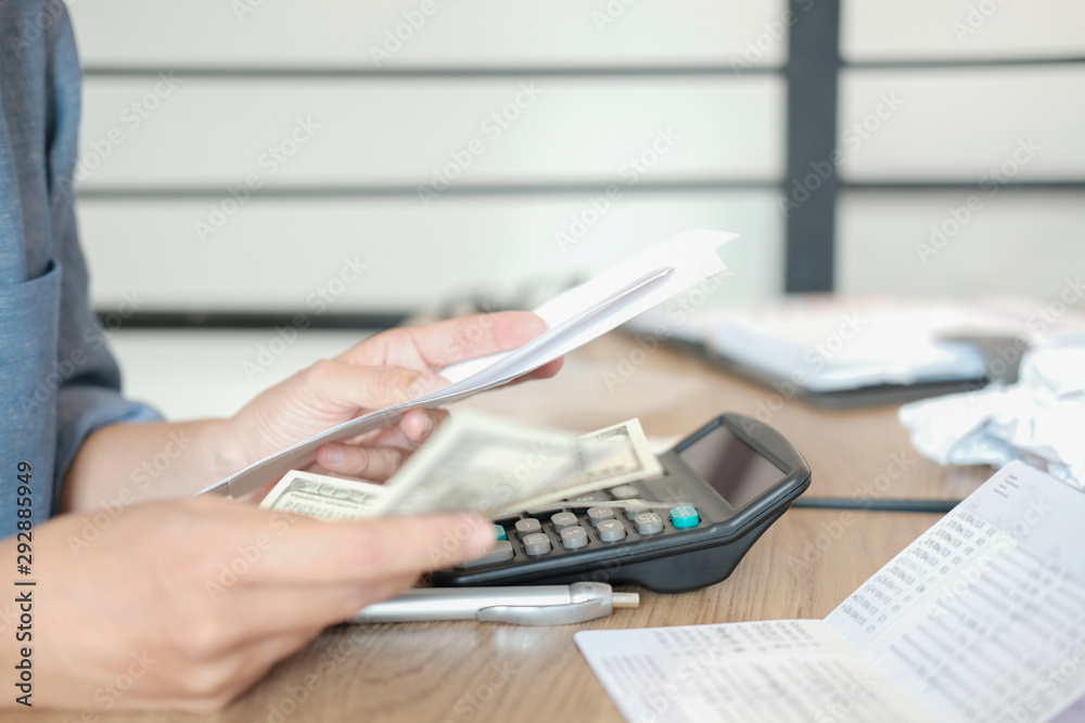 Fototapeta premium man calculate domestic bills. Businessman with calculator checking balance & costs. Startup counting finance for paying taxes