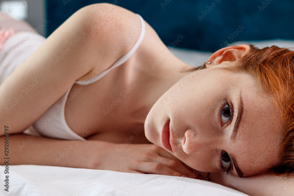 Young redheaded woman in white shirt lying on the bed. Young redheaded woman in white shirt lying on the bed.