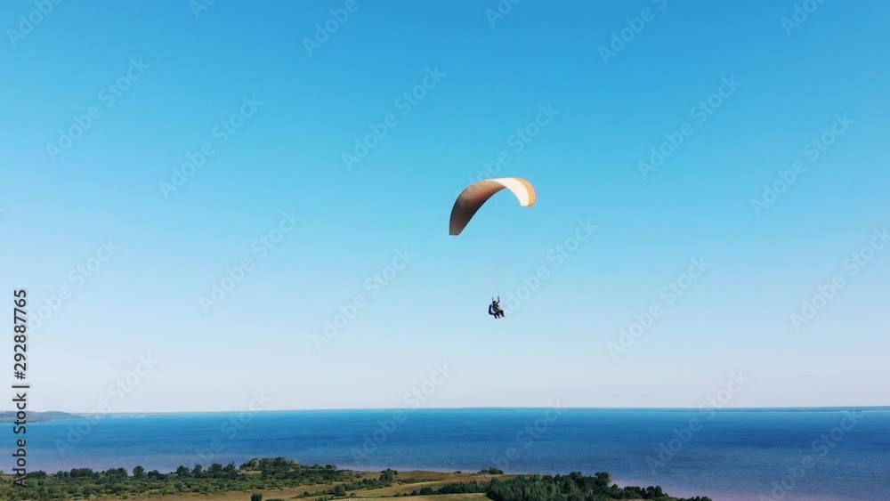 A person flies with a paraglider in the sky. A person flies with a paraglider in the sky.