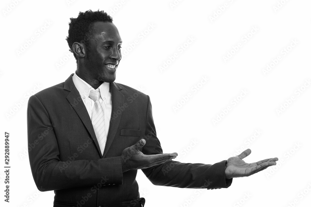 Young happy black African businessman smiling and showing something Young happy black African businessman smiling and showing something