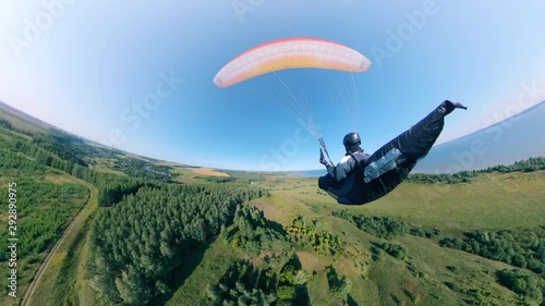 A man in helmet flying with paraplane over field. photo