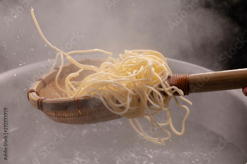 The bamboo pole picks up the hot noodles in the cauldron, and the noodle teeth have an appetite photo
