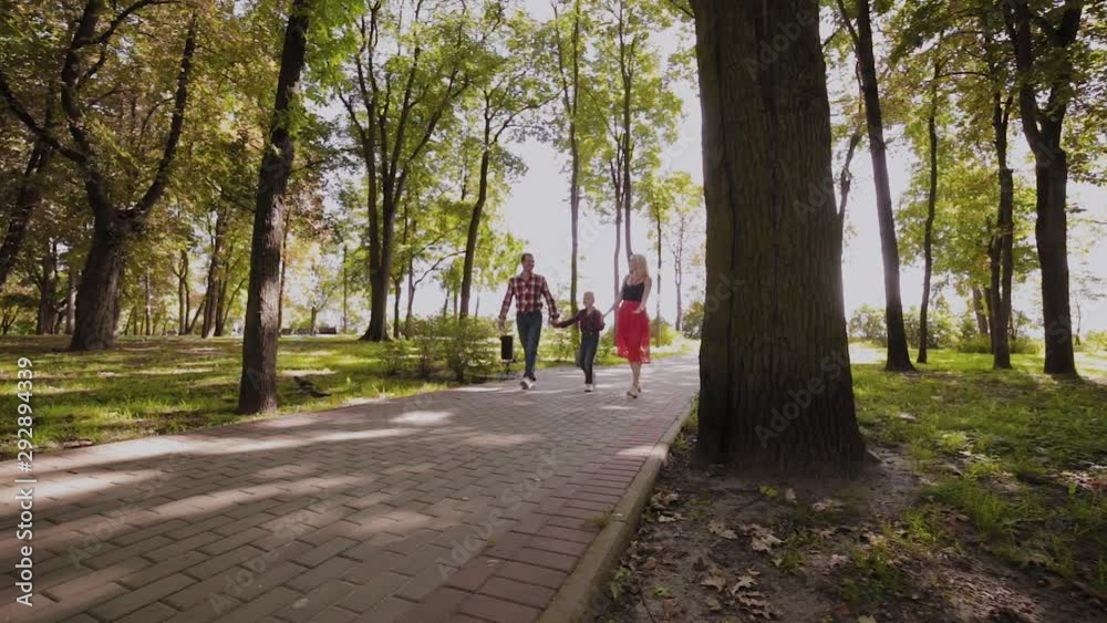 Happy young family walks in the park along the alley. Happy young family walks in the park along the alley.