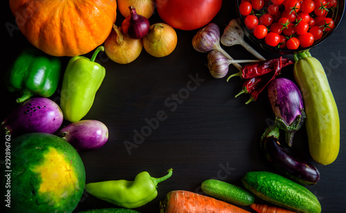 Autumn still life with pumpkin, watermelon, and a variety of colorful vegetables on black wooden background. Happy Thanksgiving background with copy space. Fresh organic food, close up.