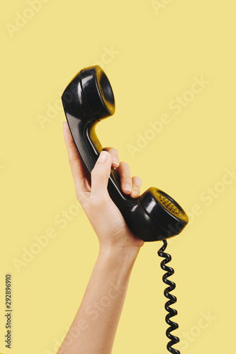 Hand of person holding black telephone receiver photo