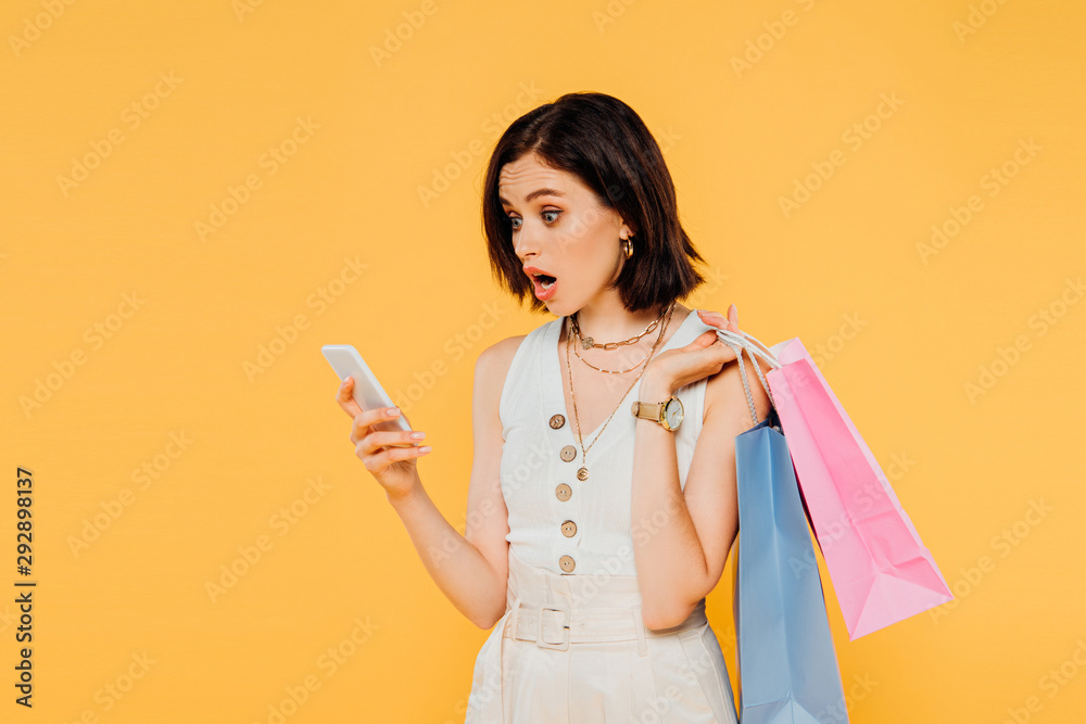 shocked girl with shopping bags talking on smartphone isolated on yellow shocked girl with shopping bags talking on smartphone isolated on yellow