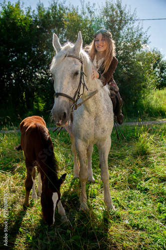 Beautiful caucasian young girl walking with a horse and enjoys summertime in countryside.
