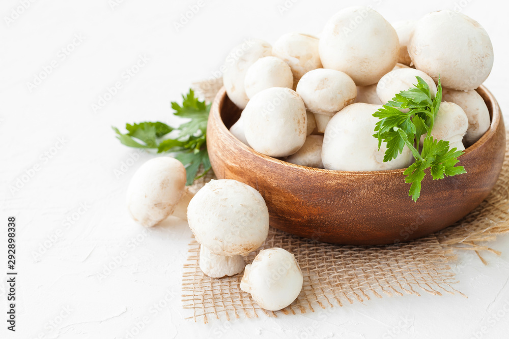 Fresh mushrooms champignon in brown bowl on white background. Fresh mushrooms champignon in brown bowl on white background.