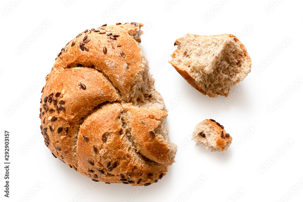 Broken whole wheat kaiser roll with linseeds and sesame seeds isolated on white. Small and big pieces. Top view. Broken whole wheat kaiser roll with linseeds and sesame seeds isolated on white. Small and big pieces. Top view.