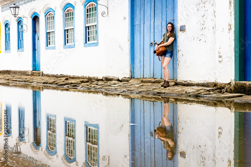 Beautiful model standing at blue wooden door in the historic city of Paraty, Rio de Janeiro, Brazil. photo