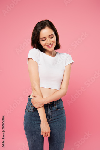 beautiful smiling shy girl looking down isolated on pink