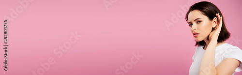 panoramic shot of beautiful focused girl listening isolated on pink