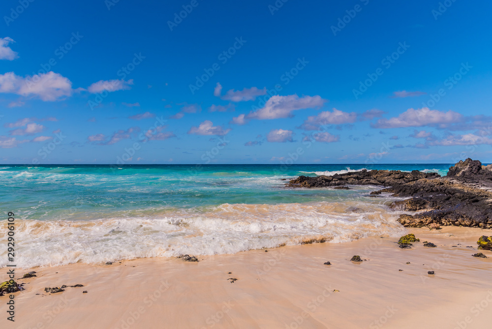 Tropical sandy beach with blue water and blue sky