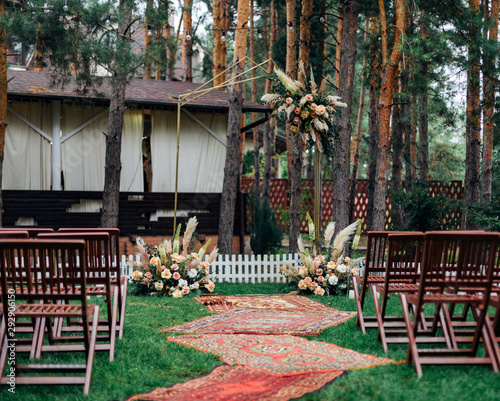 venue for the wedding ceremony in a picturesque place in a pine forest. rustic style. The arch is decorated with beautiful bouquets of flowers.