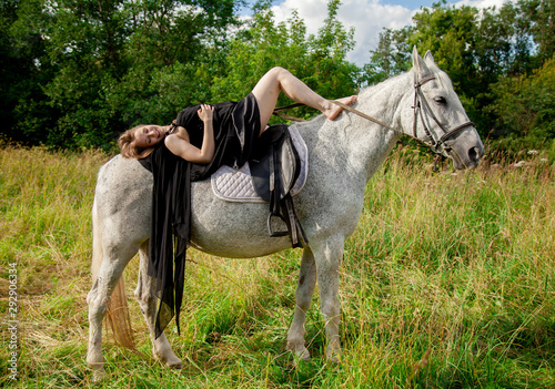 Beautiful caucasian young girl walking with a horse and enjoys summertime in countryside.