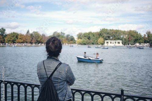 Girl or woman looking at artificial lake with boats at the The Buen Retiro Park - Parque del Buen Retiro, Madrid.