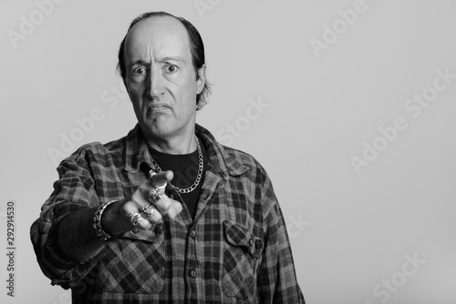 Studio shot of mature gangster man looking angry while pointing finger at camera