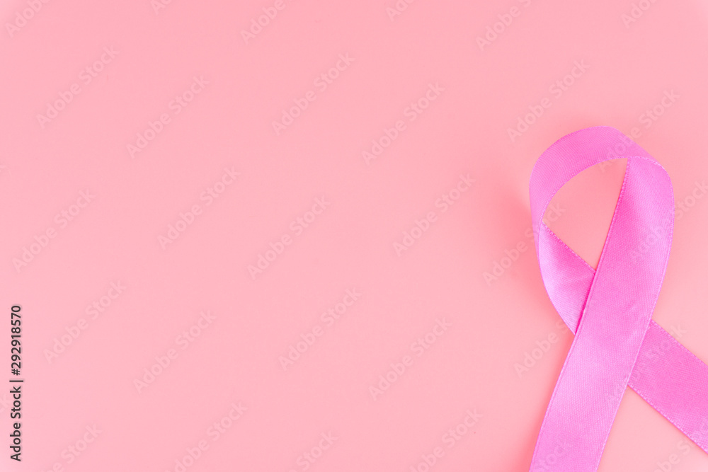 Pink ribbon breast cancer on pink background with copy space for text. Flat lay, top view.