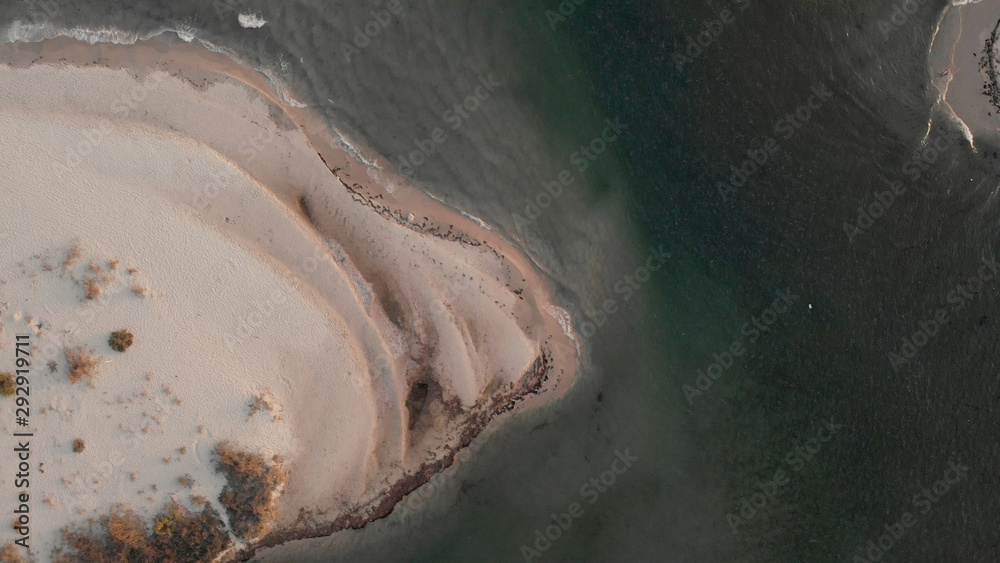 Waves rolling on sandy beach, view from above. Foaming sea waves washing a shore at the beach, view from drone.