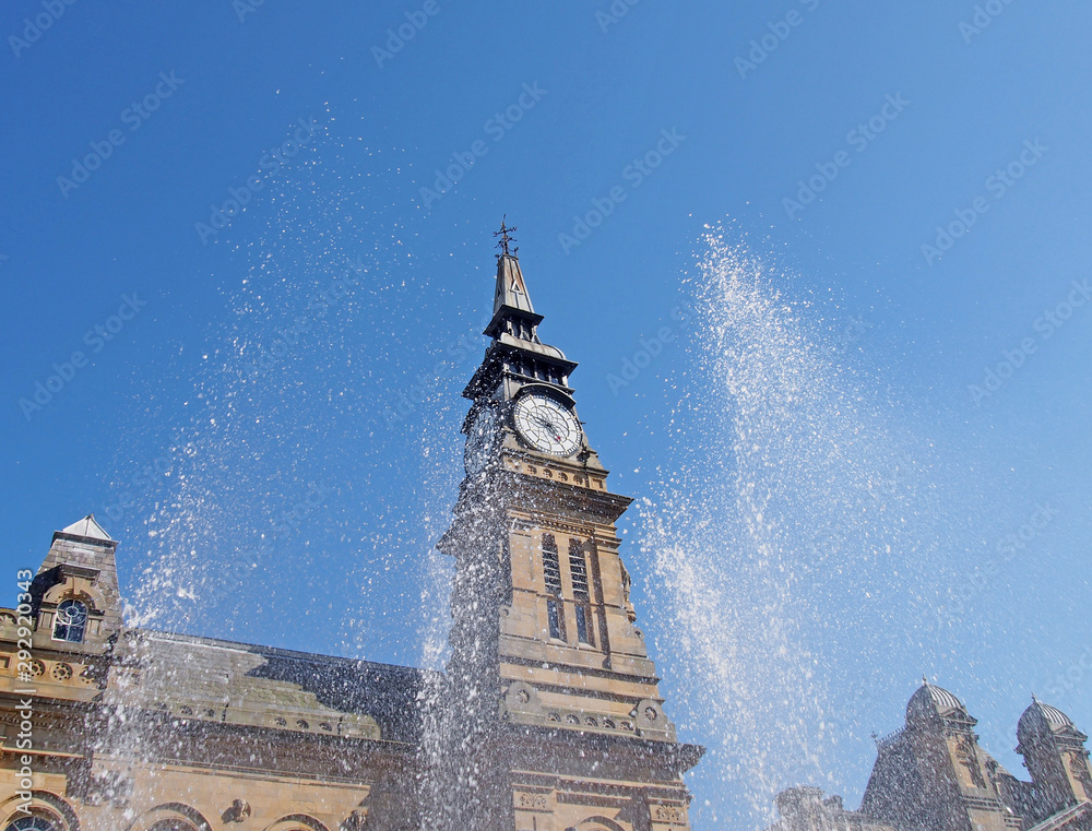 Φωτογραφία blurred splashing water from a fountain in front of the clock tower of the histo