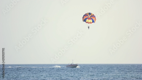 Couple of tourists flying with parachute over the sea. Summer holiday at resort.