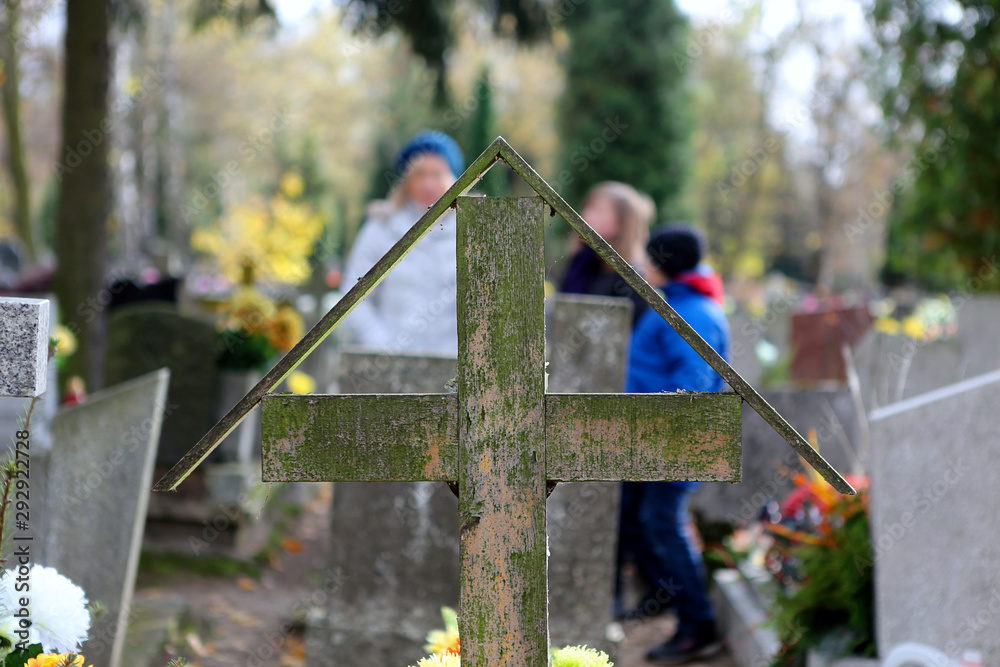 Φωτογραφία Old wooden cross in a cemetery and family in background on the feast of all sain